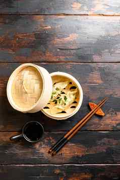 煮熟的热中国人饺子木轮船我是酱汁新鲜的草本植物筷子木表格前视图