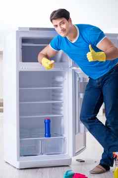 男人。清洁冰箱卫生概念