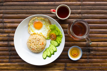 炒蛋大米新鲜的蔬菜白色板酱汁壶杯茶棕色（的）竹子表格泰国早餐前视图