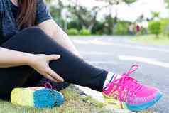 亚洲女人按摩痛苦的小腿疼痛慢跑运行公园受伤体育运动锻炼概念