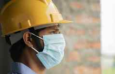 头拍摄一边视图建设工人建设建筑窗口伤心工业工人需要戴安全帽的医疗面具由于冠状病毒科维德危机