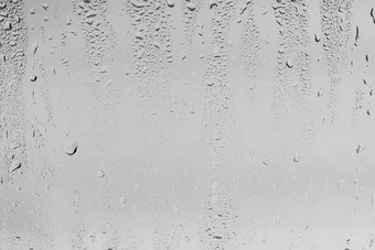 雨滴窗口眼镜表面灰色的天空背景自然背景雨滴覆盖设计概念坏多雨的天气
