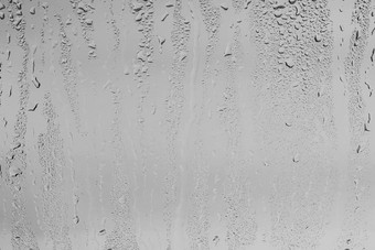 雨滴窗口眼镜表面灰色的天空背景自然背景雨滴覆盖设计概念坏多雨的天气