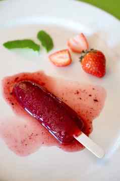 美味的解冻草莓冰棒白色轮菜绿色背景