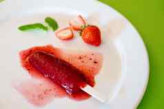 美味的解冻草莓冰棍白色轮菜绿色背景