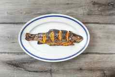 烤鳟鱼白色椭圆形板蓝色的灰色的木表格