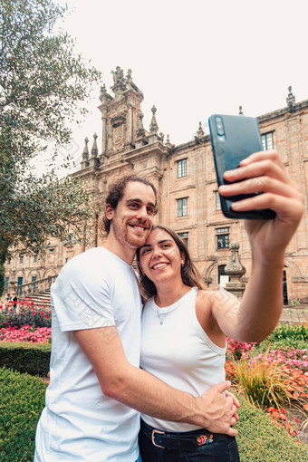 垂直拍摄年轻的夫妇采取花俏的自拍花园前面建筑