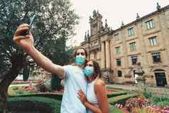 年轻的夫妇采取花俏的自拍面具花园前面建筑