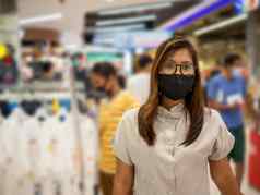 女人穿保护面具走购物中心