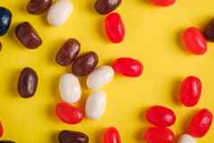 多汁的甜蜜的水果色彩斑斓的果冻豆子明亮的黄色的背景