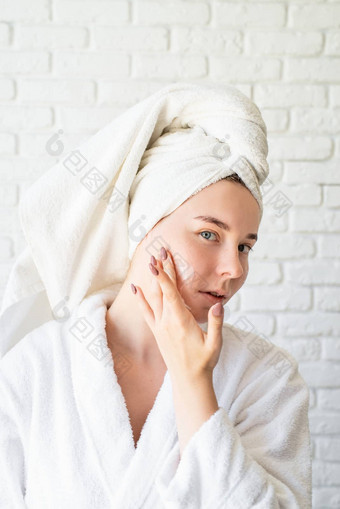 快乐年轻的高加索人女人白色浴毛巾应用脸奶<strong>油首页</strong>