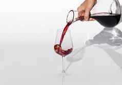 品酒 师倒红色的酒玻璃水瓶葡萄酒杯白色背景