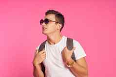 男人。太阳镜背包白色t恤青年风格粉红色的背景