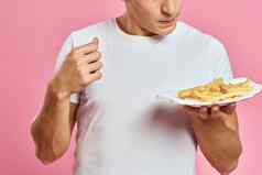 男人。法国薯条纸盒子粉红色的背景卡路里快食物肖像粉红色的背景