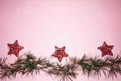 松柏科的分支机构红色的星星圣诞节树装饰一年的粉红色的背景复制空间