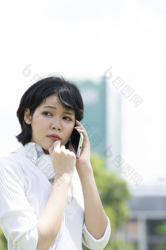 令人担忧的亚洲女人使电话调用花园