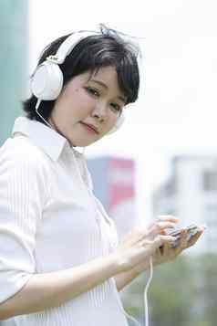 快乐亚洲女人听音乐移动电话花园