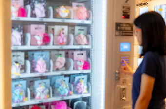 模糊亚洲女人紧迫的按钮自动售货机买娃娃