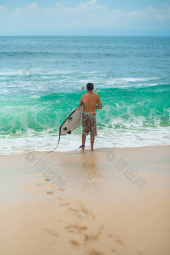 冲浪者冲浪男人。冲浪板走桑迪热带海滩健康的生活方式水活动水体育运动美丽的海洋