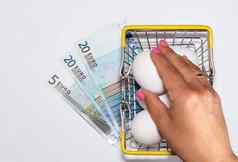 新鲜的鸡蛋购物车欧元账单下面女士手达到鸡蛋购物采购食物交付概念
