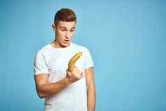 快乐男人。新鲜的水果手势手蓝色的背景白色t恤维生素香蕉
