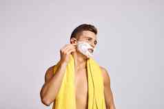 男人。黄色的毛巾肩膀橙色剃须刀白色泡沫清洁皮肤