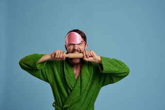 男人。粉<strong>红色</strong>的睡眠面具持有<strong>滚动</strong>销手绿色袍蓝色的背景情绪模型