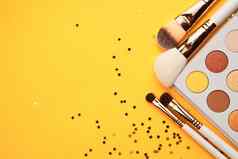 眼影膏刷化妆闪闪发光的黄色的背景专业化妆品
