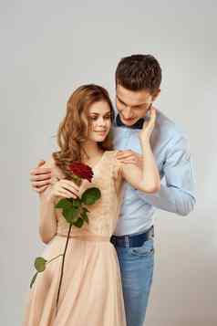 年轻的夫妇浪漫拥抱的关系约会红色的玫瑰光工作室背景