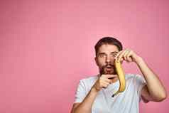 有胡子的男人。香蕉手粉红色的背景有趣的情绪模型