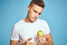 快乐男人。新鲜的水果手势手蓝色的背景白色t恤维生素苹果
