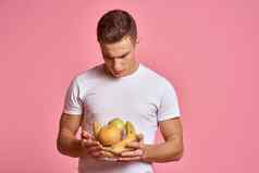 男人。水果手粉红色的背景健康的食物维生素粉红色的背景白色t恤模型