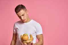 男人。水果手粉红色的背景健康的食物维生素粉红色的背景白色t恤模型