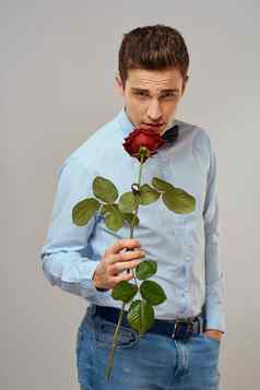 浪漫的男人。红色的玫瑰蓝色的衬衫弓领带脖子灰色的背景