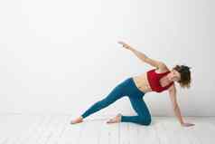 女人蓝色的牛仔裤实践瑜伽光背景在室内苗条的数字体操