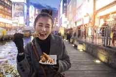 年轻的女人游客享受吃街食物走压力