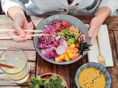 女人吃美味的色彩斑斓的健康的自然有机素食者夏威夷戳碗亚洲筷子乡村木表格健康的自然有机吃概念