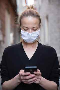 科维德流感大流行冠状病毒休闲高加索人女人中世纪的城市街移动电话穿保护脸面具传播冠状病毒疾病传输
