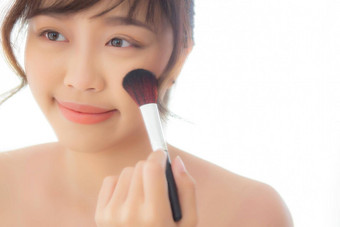 美肖像年轻的亚洲女人微笑脸镜子应用化妆刷脸颊卧室美丽的女孩持有脸红的人皮肤护理化妆品概念