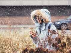 微笑女人光蓝色的温暖的夹克发短信智能手机在线沟通LTE无线网络无线细胞技术秋天季节小镇