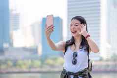 美丽的亚洲旅游女人视频调用智能手机城市城市市中心假期旅行夏天