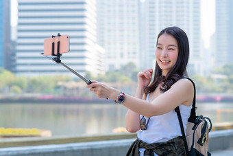 美丽的亚洲旅游女人<strong>视频</strong>调用智能手机<strong>城市城市</strong>市中心假期旅行夏天