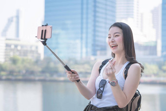 美丽的亚洲女人享受视频调用技术智能手机城市城市市中心