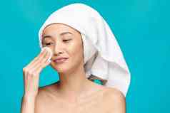 漂亮的女人擦拭脸棉花垫清洁皮肤健康蓝色的背景