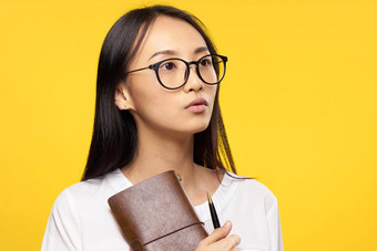 亚洲女人眼镜记事本笔<strong>手办</strong>公室经理黄色的背景