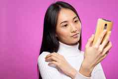 女人亚洲外观电话手特写镜头技术小工具粉红色的背景