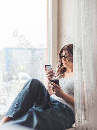 深思熟虑的女人眼镜杯热咖啡智能手机信息在线媒体