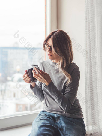 深思熟虑的女人眼镜杯热咖啡智能手机信息在线媒体