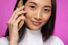 微笑亚洲女人会说话的电话技术粉红色的背景
