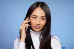 亚洲女人四肢会说话的电话蓝色的背景工作室